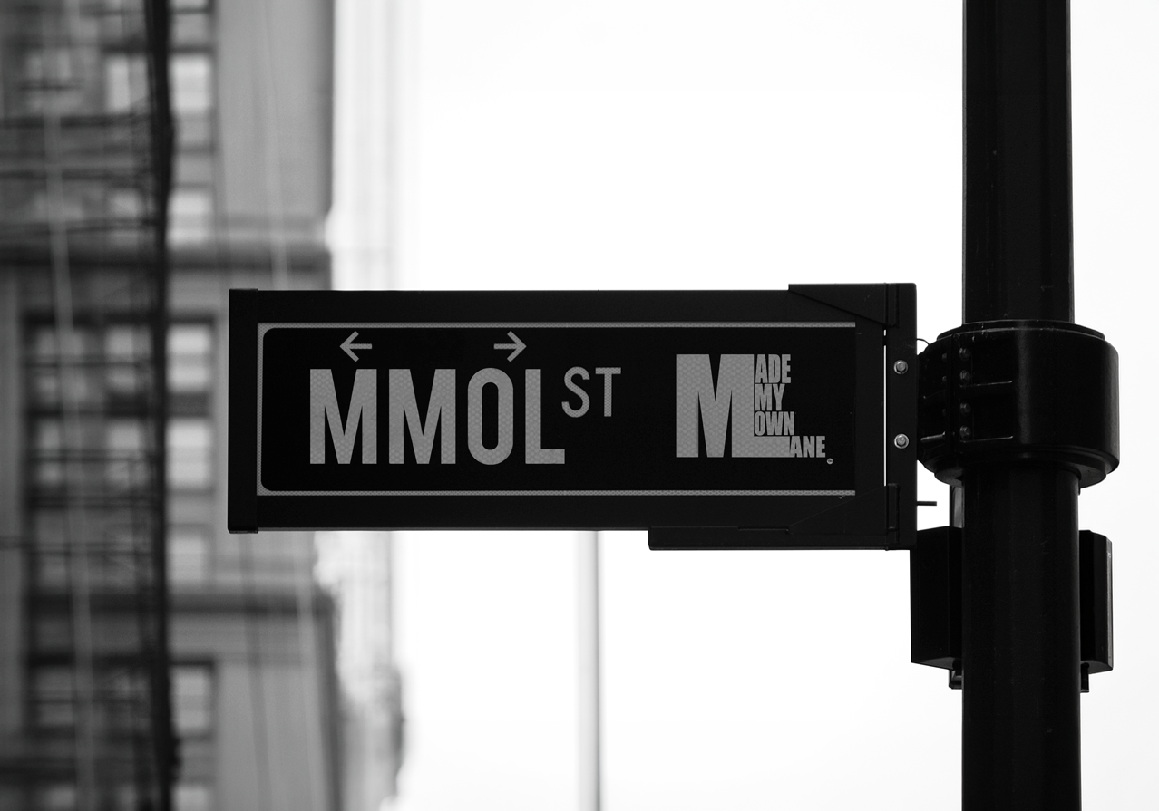 A black and white MMOL street sign mounted on a city pole.